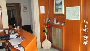 A reception desk with a vase of flowers, a framed picture, and a map on the wall. - Ca Grande (Milan)