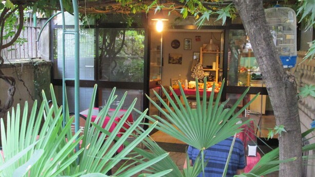 A room with a glass door leading to a dining area, a small table with chairs, and a hanging light fixture. - Ca Grande (Milan)
