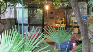 A room with a glass door leading to a dining area, a small table with chairs, and a hanging light fixture.