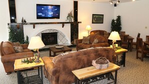 A cozy living room with a fireplace, comfortable seating, and a flat-screen TV mounted on the wall. - Thunderbird Resort Club (Sparks)