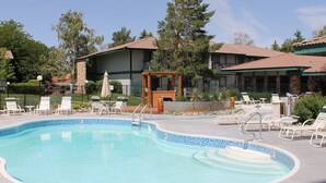 A swimming pool with lounge chairs and a wooden pergola, surrounded by buildings with red-tiled roofs. - Thunderbird Resort Club (Sparks)