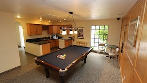 A pool table in a room with a kitchen area, a dining table, and chairs. - Thunderbird Resort Club (Sparks)