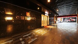 A modern hotel lobby with a checkered floor, a reception desk, and a visible emergency exit. - Hotel Valentine (Seoul)