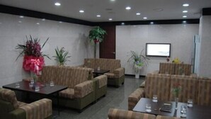 A conference room with multiple sofas and tables, a large plant, and a screen on the wall. - Hotel Valentine (Seoul)