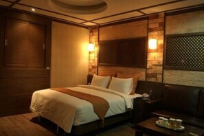 A hotel room with a large bed, a wooden headboard, and a small table with a tray of items. - Hotel Valentine (Seoul)