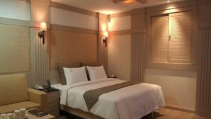 A hotel room with a bed, bedside tables, a nightstand, a lamp, and a window with blinds. - Hotel Valentine (Seoul)