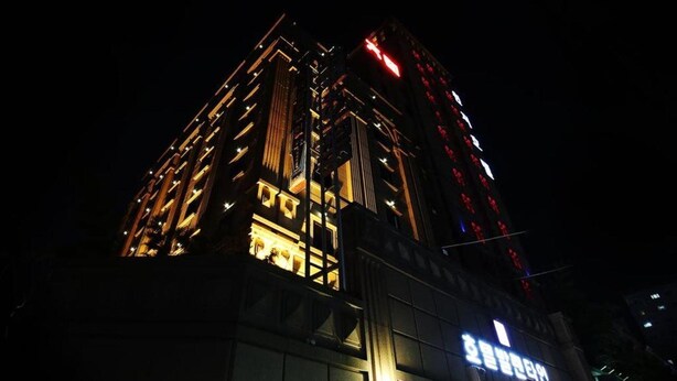 A modern high-rise building with illuminated windows and a prominent red sign on the side. - Hotel Valentine (Seoul)