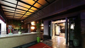 A hotel lobby with a reception desk, potted plants, and a red carpet with the hotel name. - Hotel Valentine (Seoul)