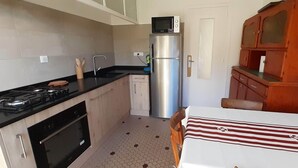 A compact kitchen with a gas stove, oven, microwave, and a refrigerator. - MAISON DE MARITXU - Between beach and forest - Landes - Pays Basque (Tarnos)