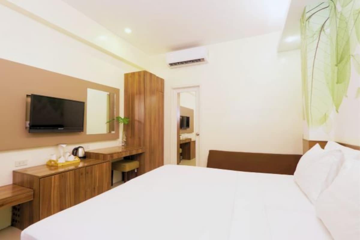 A hotel room with a bed, a desk, a television, and a mirror.