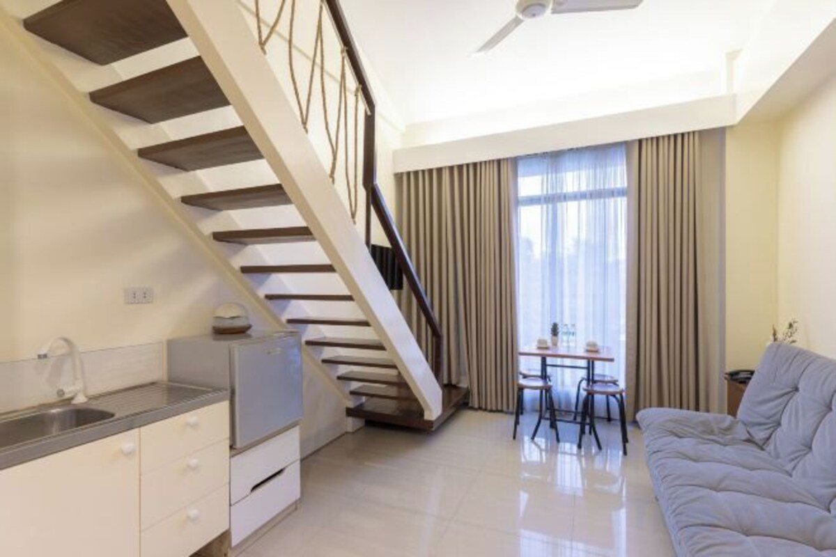 A modern living space with a kitchen, dining area, and a staircase.