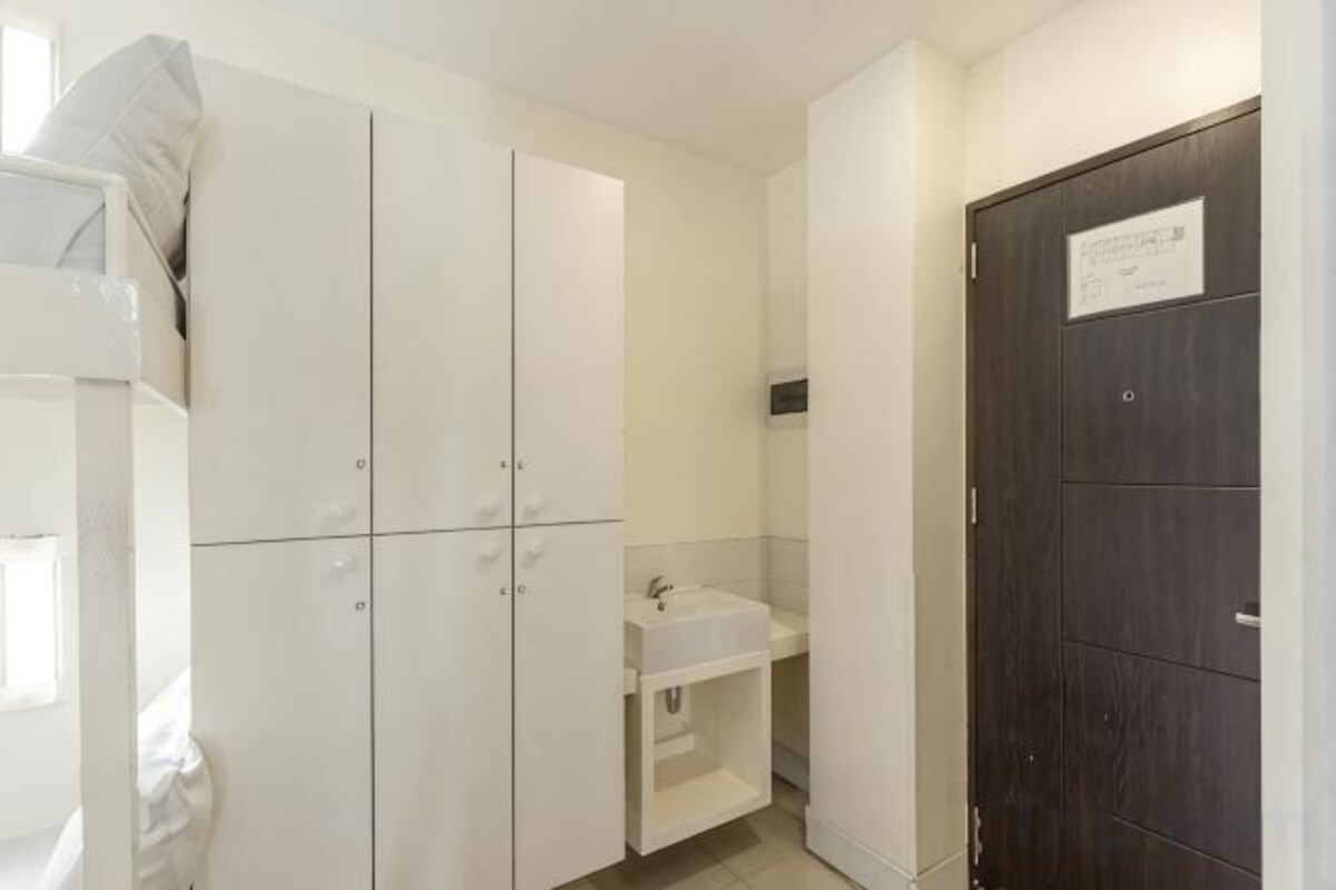 A hotel room with a wardrobe, a sink, and a dark door.