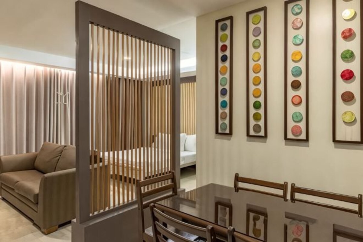 A modern interior with a sofa, a dining table, and a decorative partition.