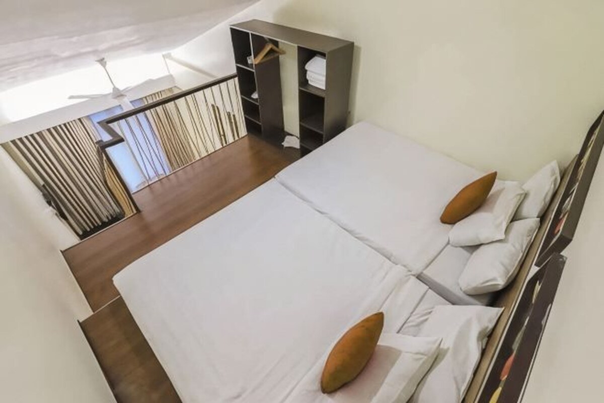 A bedroom with two beds, a wardrobe, and a view of the outside.