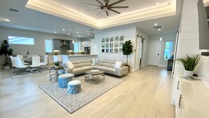 A spacious living room with a large L-shaped sectional sofa, a coffee table, and a ceiling fan. - Enjoy a new construction home with heated salt pool close to everything Naples (Naples)