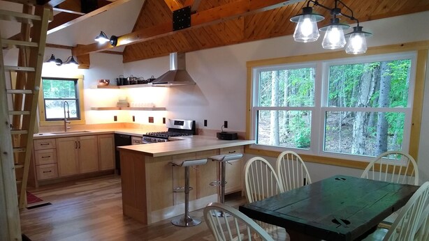 Ett modernt kök med träskåp, en köksö, barstolar och ett matbord med vita stolar.