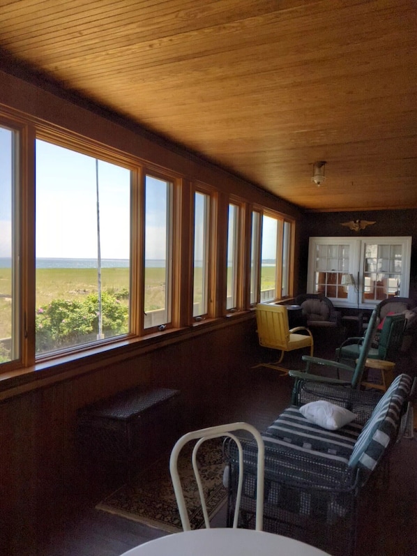 A room with large windows, a wooden ceiling, and a view of the outdoors.