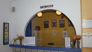 A reception area with a blue counter, framed artwork, and a sign reading "RECEPCION". - Virgen del Mar (Mojacar)