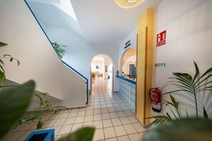 A hotel corridor with a staircase, a fire extinguisher, and a sign indicating an exit.