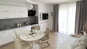 A modern kitchen with a dining area, a flat-screen TV, and a sofa in a living space. - Luxuroese Apartments mit Privatem Pool und Jacuzzi (Biograd na Moru)