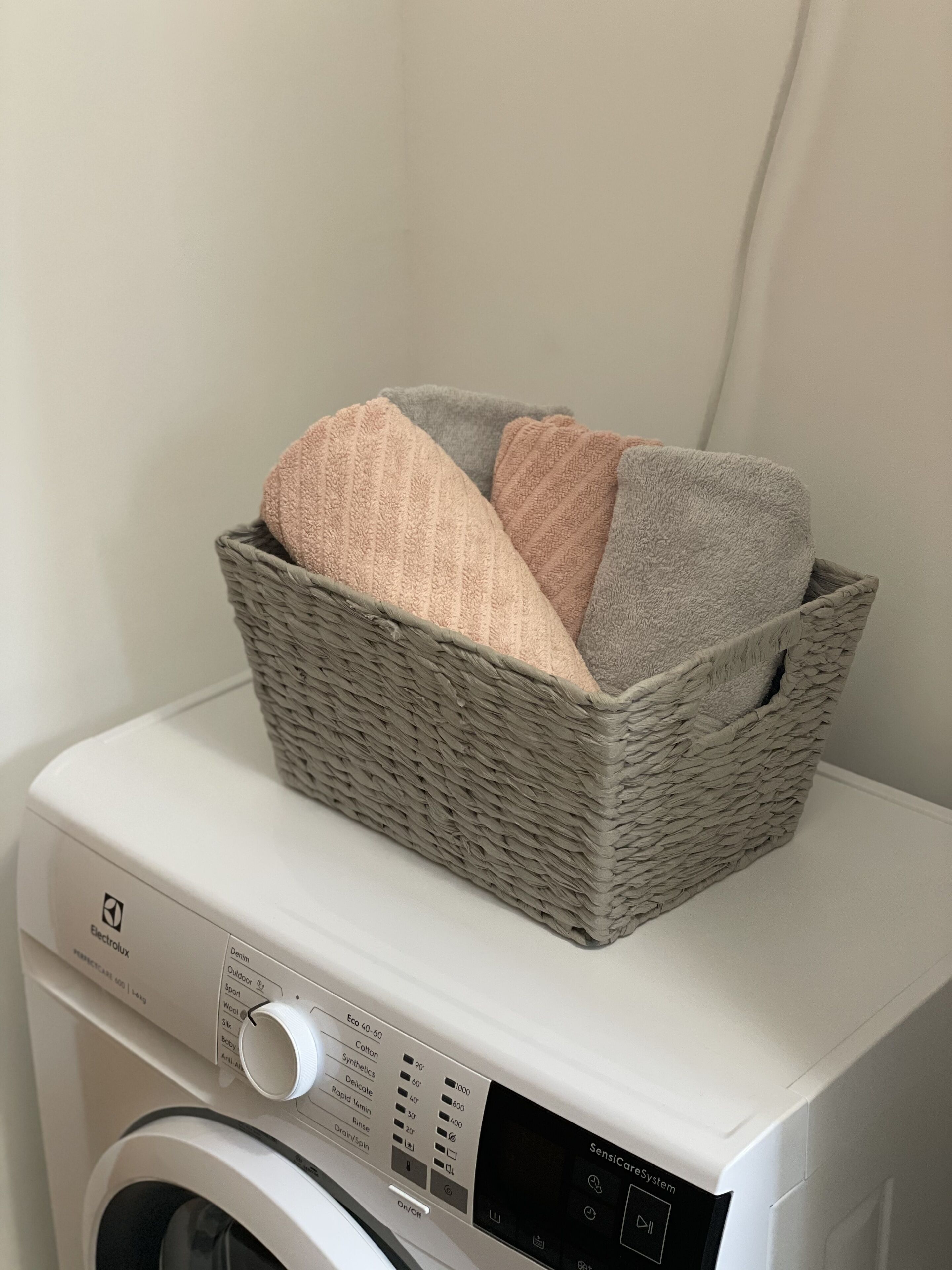 En vaskemaskine med en kurv fyldt med foldede håndklæder ovenpå.