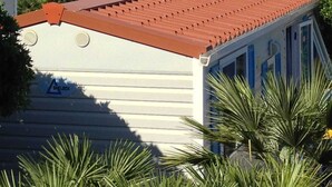 Un bâtiment blanc avec un toit rouge, une montagne en arrière-plan et des arbres verts au premier plan.