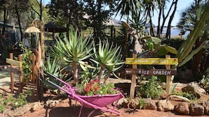 Un jardin avec un panneau en bois indiquant « GARDINO DELLE ROSE » et « ROSE GARDEN ».