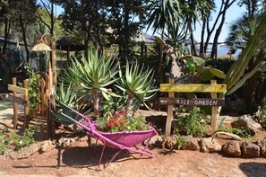 Een tuin met een houten bord waarop 'GARDINO DELLE ROSE' en 'ROSE GARDEN' staat.