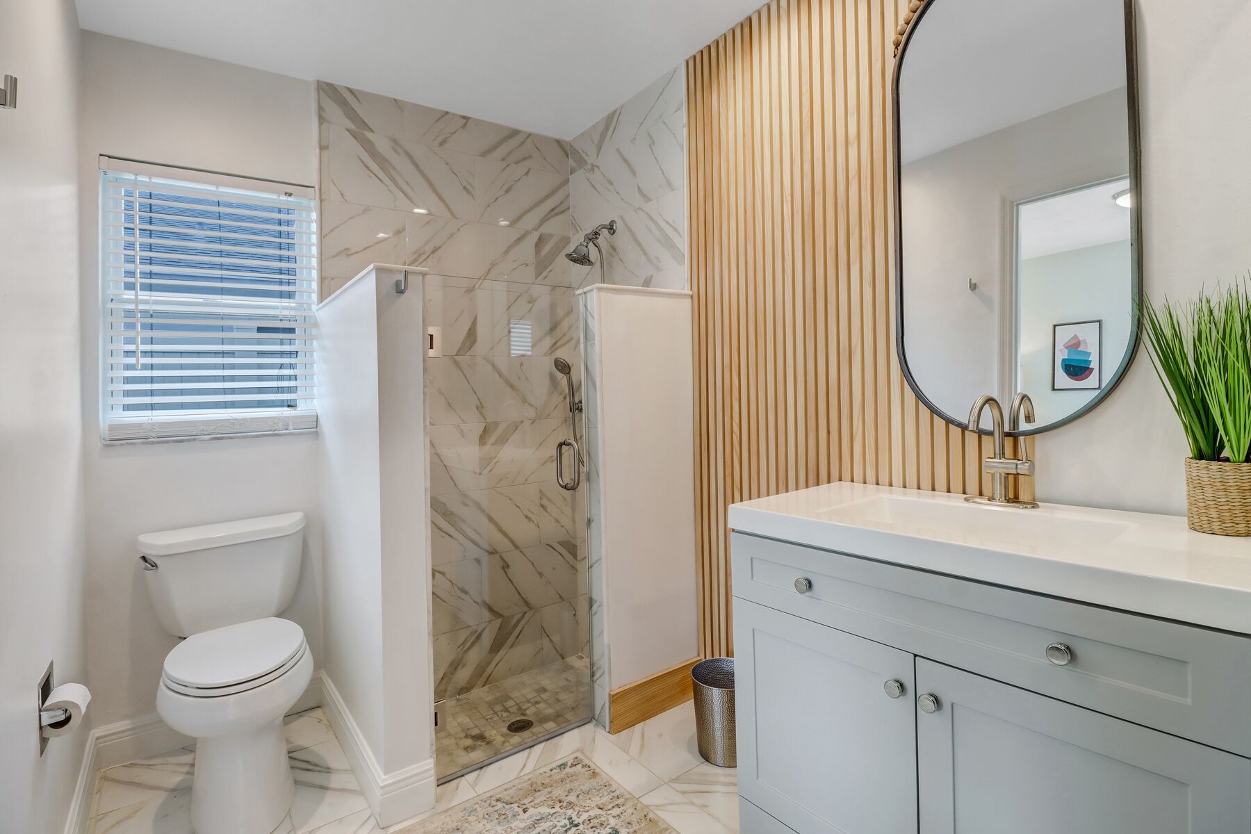 Bagno con toilette, doccia e lavabo con specchio.