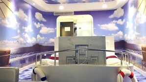 A room with a ceiling mural of clouds and a sea scene, a bed, a desk, and a life ring. - Grand Nest Hotel (Zhuhai)