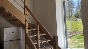 Une cuisine moderne dotée d’un réfrigérateur encastré et d’un escalier en bois menant à une mezzanine.