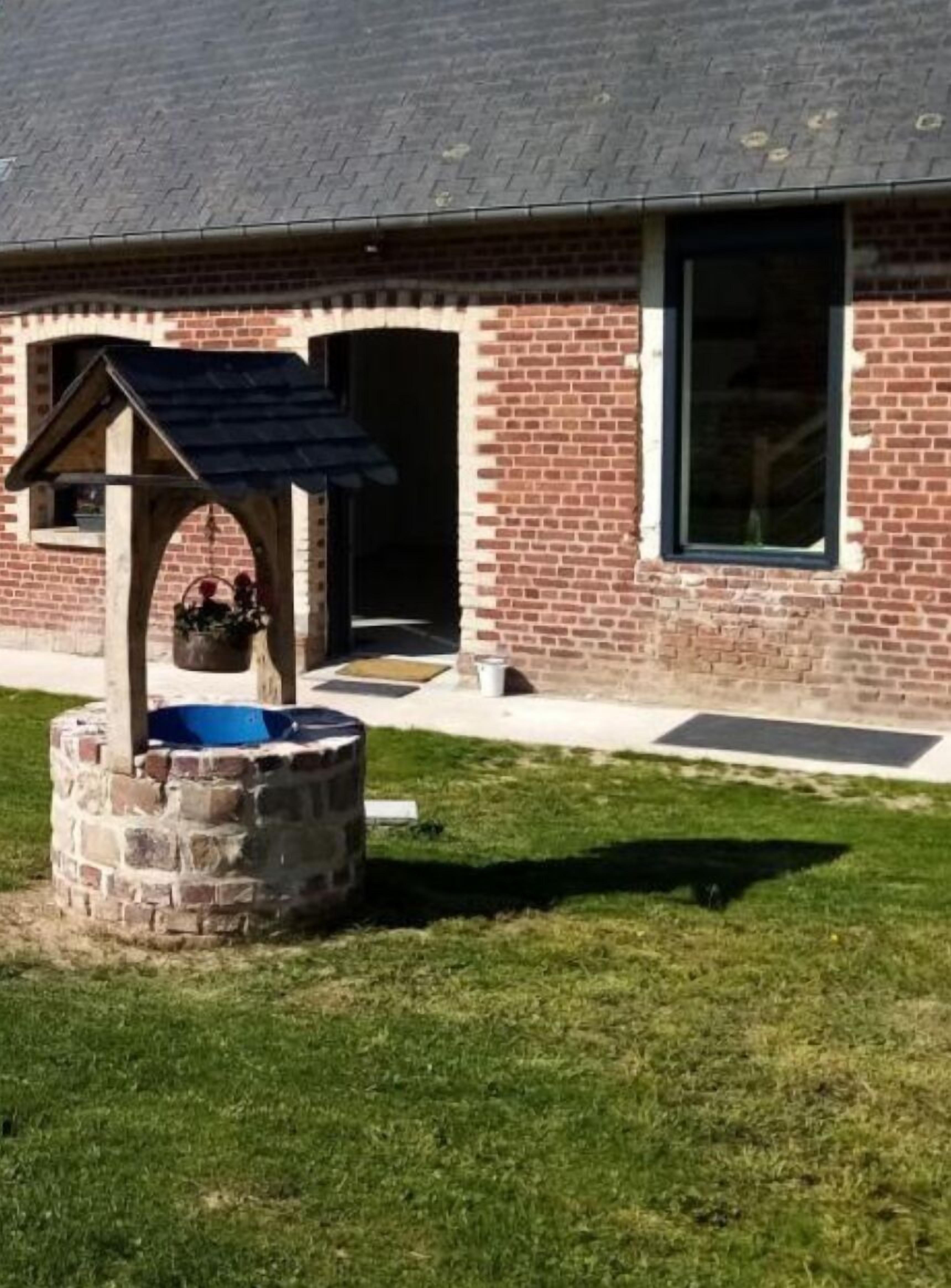 A brick building with a stone well and a covered area.