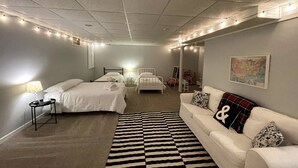 Een hotelkamer met twee bedden, een witte bank, een vloerkleed met dessin en sfeerverlichting aan het plafond.
