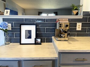 Enjoy a stylish kitchen with a black and white backsplash, marble countertop, and high-end espresso machine.