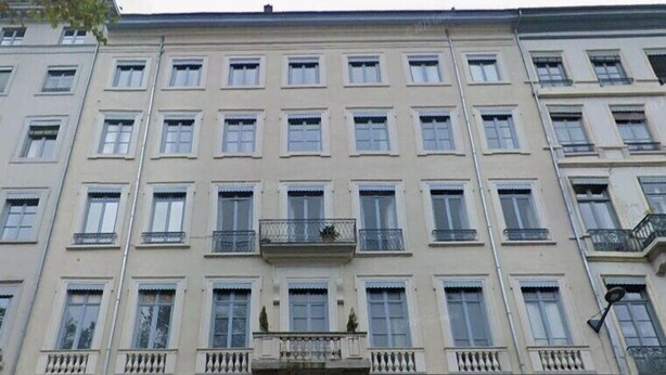Un edificio de varios pisos con fachada simétrica, ventanas amplias y una entrada central con balcón decorativo.