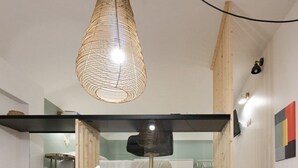 Un interior moderno con una escalera, una lámpara colgante y una puerta decorada con un diseño geométrico.