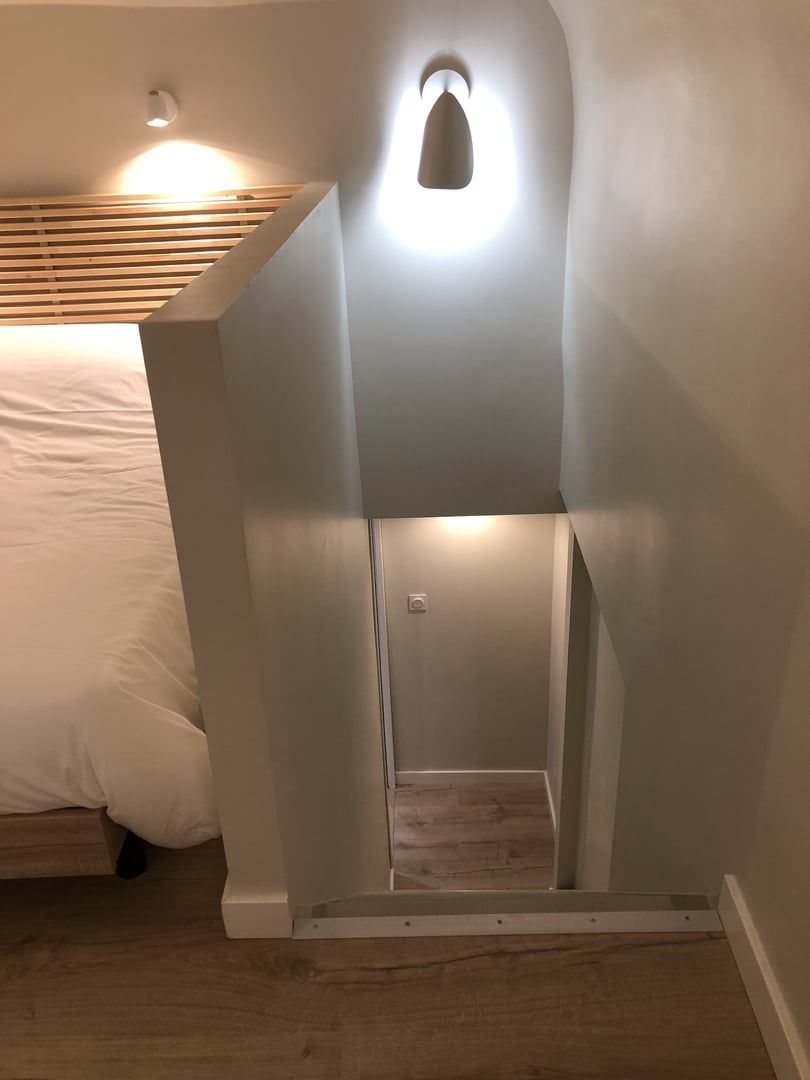 A room with a sloped ceiling, a bed, and a small window.