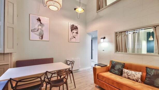 A spacious room with a dining table, chairs, a sofa, and two wall-mounted lamps. - Quiet and cozy 3-bedroom flat – Terreaux/Opéra (Lyon)