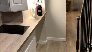 A modern kitchen with white cabinets, a black induction cooktop, and a wooden countertop. - Quiet and cozy 3-bedroom flat – Terreaux/Opéra (Lyon)