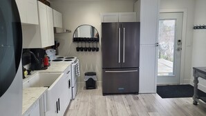 Une cuisine moderne avec des meubles blancs, un réfrigérateur en acier inoxydable, une cuisinière et un évier.