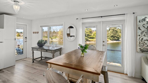 Une cuisine spacieuse avec une table en bois, un tabouret de bar et une vue sur un lac grâce à de grandes fenêtres.