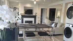 Une cuisine moderne avec un îlot central, un coin repas avec une table et des chaises, un canapé et un lave-linge.