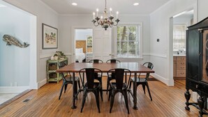 Un comedor con una mesa y sillas de madera, un candelabro y vistas al exterior a través de una ventana.