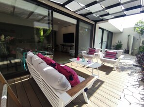 Eine moderne Terrasse im Freien mit einem weißen Sofa, einem kleinen Tisch und zwei Stühlen.