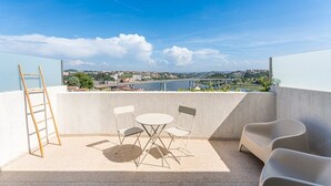 A balcony with a table and chairs, a ladder, and a view of a bridge and river. - GuestReady - Freixo Island - Douro Views (Porto)