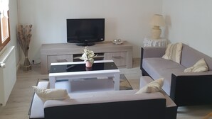 A living room with a sofa, a coffee table, a TV, and a lamp.