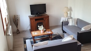 A living room with a sofa, a coffee table, a television, a lamp, and a fireplace.