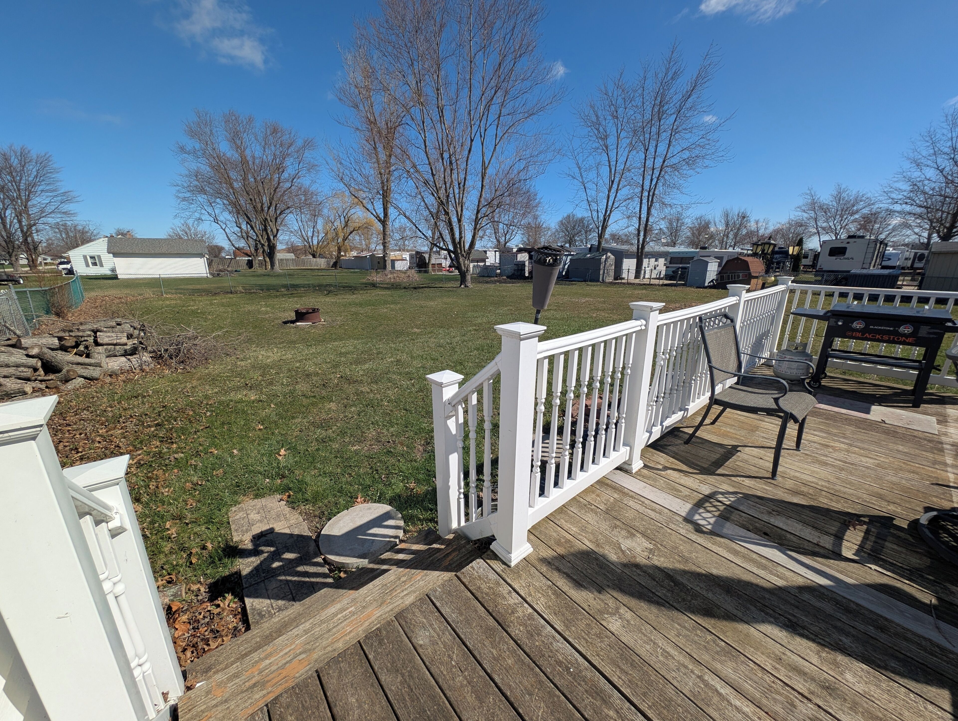 Une terrasse en bois avec une balustrade blanche, un chemin de pierre et une pelouse.