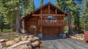 Eine Blockhütte mit Balkon, Garage und Eingang aus Stein.