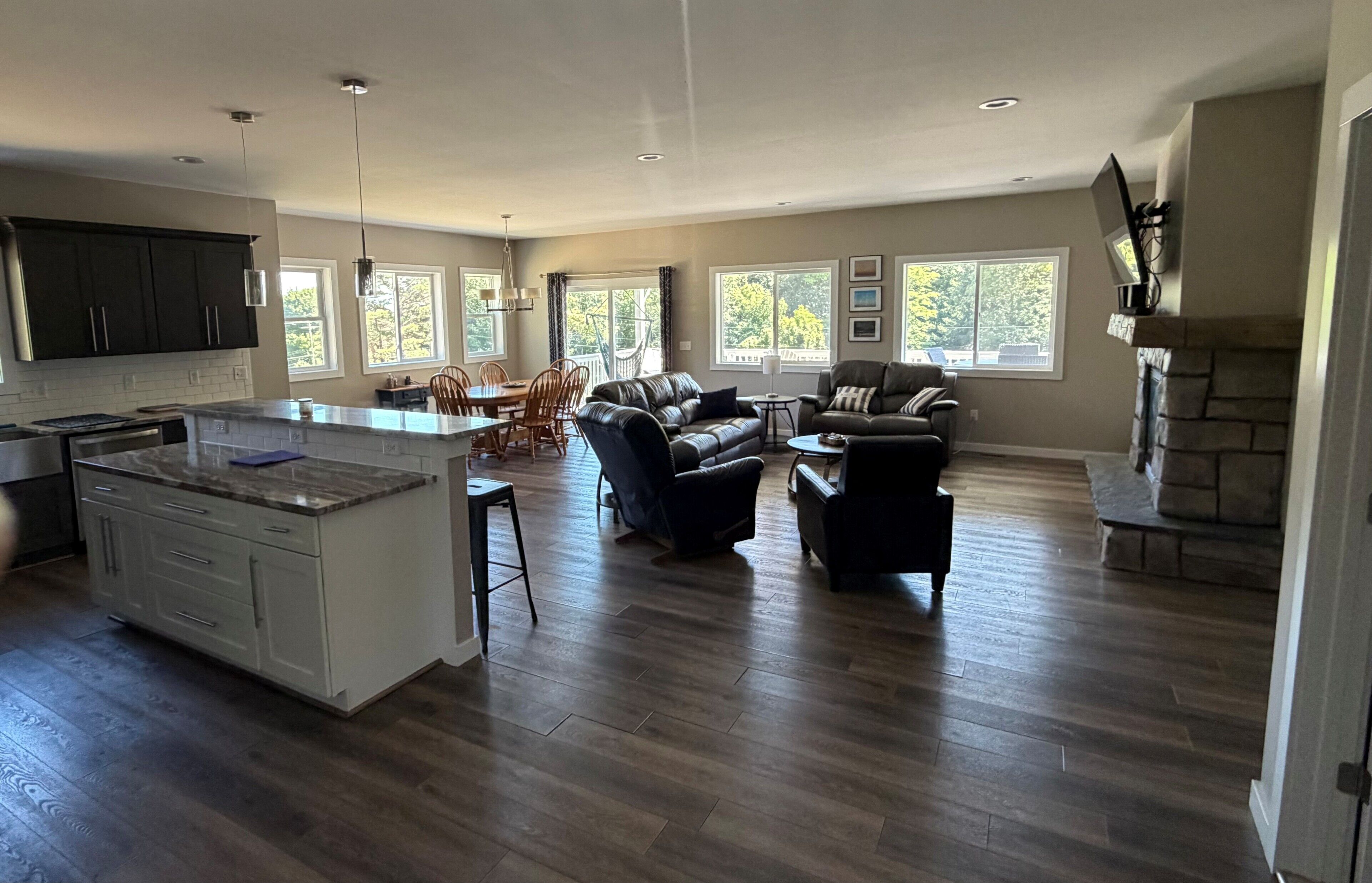 A spacious living area with a large island, dark wood flooring, and a fireplace.